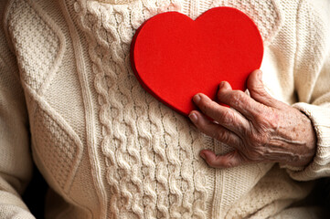 Closeup of old woman hand hold red heart -  concept of heart health and quality of life for elderly
