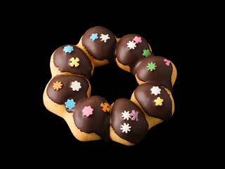 Cookies in the form of a ring in glaze and confetti on a black background.