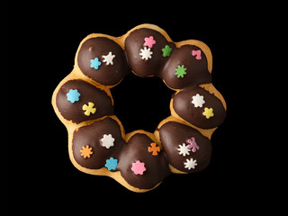 Cookies in the form of a ring in glaze and confetti on a black background.