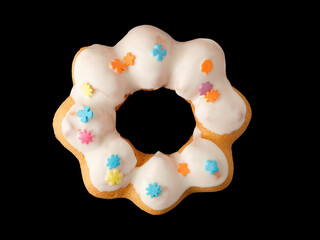 Cookies in the form of a ring in glaze and confetti on a black background.