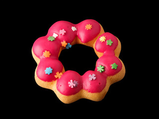 Cookies in the form of a ring in glaze and confetti on a black background.