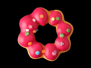 Cookies in the form of a ring in glaze and confetti on a black background.