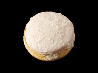 Closed donut in white glaze with on a black background.