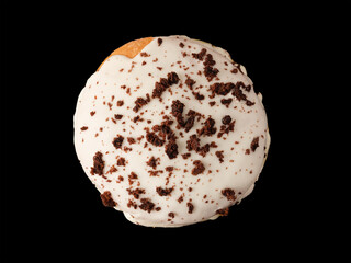 Closed donut in white glaze with chocolate chips on a black background.