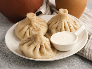 Khinkali in a white plate with sauce.
