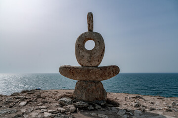 Fototapeta na wymiar Sculpture symbol made of large pebbles against the blue sky