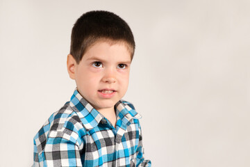 A 4-year-old preschool boy looks up belligerently, frowning his eyebrows on a white background with...