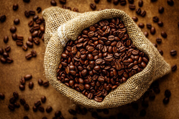 Coffee sack top view over grunge background with scattered roasted beans. Selective focus, shallow...