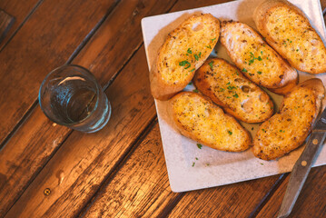 Garlic bread in a plate placed on a wooden table