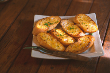 Garlic bread in a plate placed on a wooden table