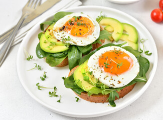 Bread with fried eggs, avocado and greens