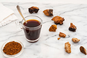 Close-up of chaga mushroom pieces, powder and infusion in a cup
