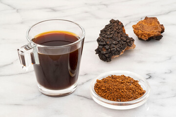 Close-up of chaga mushroom pieces, powder and infusion in a cup