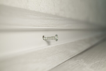 Installation of plastic skirting board in the room. Screwing to the wall of the baseboard. Repair in the house with your own hands. Selective focus