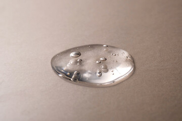 A drops of transparent cosmetic gel on a beige background.