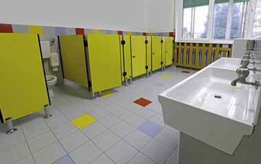 interior of the kindergarten toilets with yellow cubicles and low sinks made especially for children