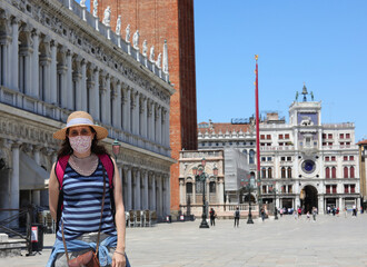 Obraz premium young cute woman with straw hat and surgical mask is a curious tourist in Venice Saint Mark Square