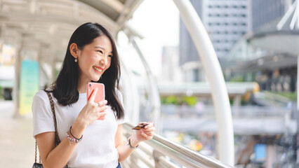 Young adult asian woman using creadit card and smartphone for online shopping and digital wallet