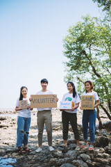 Group of volunteers hold a volunteer sign in world environment day event, volunteer conservation pick up plastic and foam garbage on mangrove forest area.Volunteering save world concept.