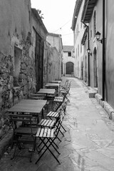 Fototapeta na wymiar Narrow pedestrian street with empty cafe tables and chairs in Limassol Old town, Cyprus