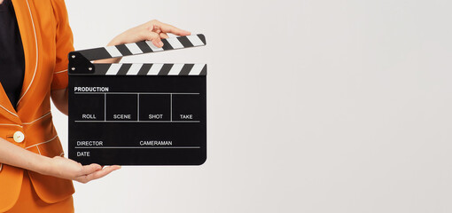 The woman's body part hold a Black Clapperboard or movie Clapper board and she wears a yellow...