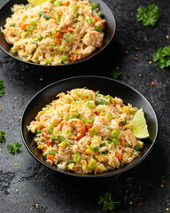 Prawn fried rice with eggs and vegetables in black bowl. Healthy asian food.