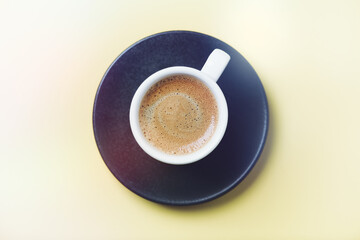 Cup of coffee on yellow background. Top view. Close up. Copy space.