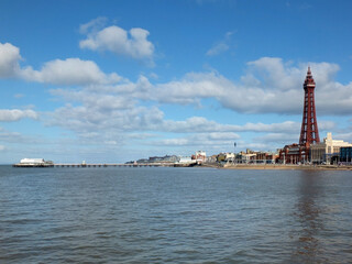Fototapeta premium view of of blackpool with the north pier buildings and tower reflected in the sea with a blue cloudy sky