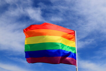 Realistic rainbow flag of LGBT organization waving against sky. LGBT pride flags include lesbians, gays, bisexuals and transgender.