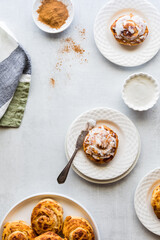 Cinnamon buns on plates served with cream cheese icing.