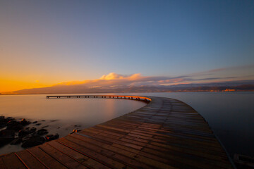 Boomerang shaped pier by the sea photographed with long exposure technique.