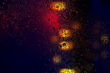 Water drops and condensation in a window glass. Abstract background niglt light