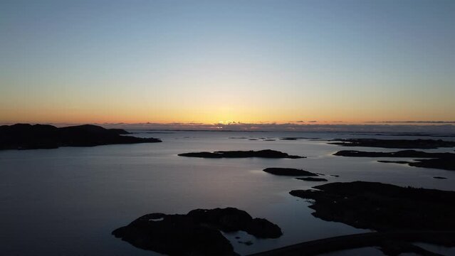flying into the sunset over the sea and archipelago aerial overview video from heroy island in Nordland