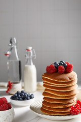 Crêpes sur une assiette couvert de fruits rouges: myrtilles, framboises. Le bouteille de lait à...