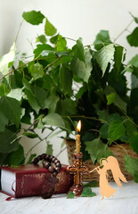 Candle, angel decor and green birch leaves on table. Holy Trinity Sunday. festive traditional...
