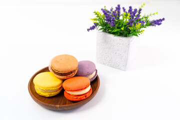 Obraz na płótnie Canvas Multicolored macarons on a wooden plate on a white background.