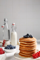 Crêpes sur une assiette couvert de fruits rouges: myrtilles, groseilles. Le bouteille de lait à...
