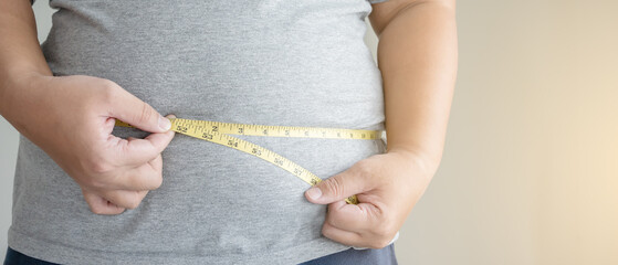 An obesity using measuring tape to show the real size. Chubby fat man using measure tape at his belly.