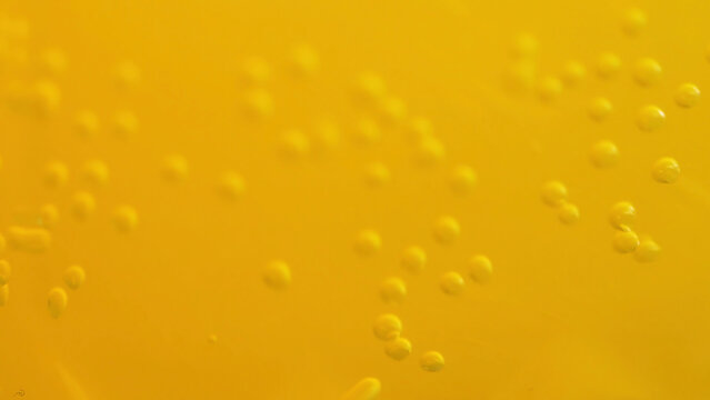 Orange soda with bubbles background. Fresh orange fruit in a glass of soda water. Orange summer drink with bubbles. Bubbles floating in the liquid orange drink.