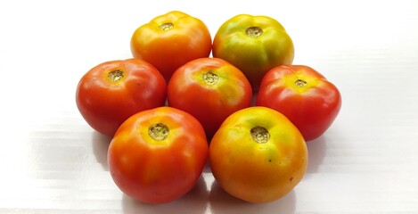 Bunch of healthy vegetable raw and ripe organic farm fresh red and yellow tomatoes isolated stacked together on white chopping board table background with copy space. Beautiful closeup macro side view