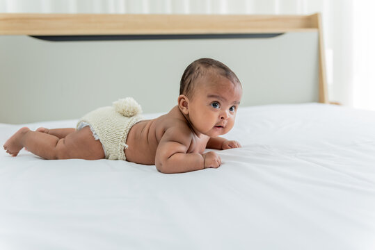 Portrait images of African baby newborn girl is 3 month year old, Lying prone on white bed in bedroom, to African newborn concept.