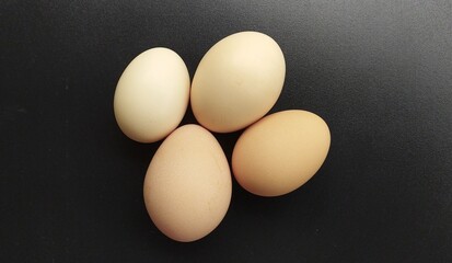 Group of several farm fresh organic brown and white uncooked raw chicken, hen, bird or duck eggs isolated on a black shiny background with copy space. Beautiful horizontal closeup macro top view.