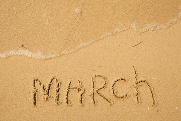 Fototapeta na wymiar March - handwritten on the soft beach sand.