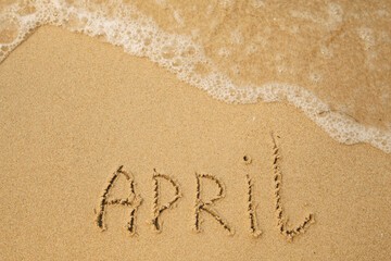 Fototapeta na wymiar April - handwritten on the soft beach sand.
