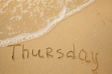 Thursday - handwritten on the light beach sand with a soft wave lapping.
