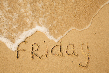 Friday - handwritten on the light beach sand with a soft wave lapping.