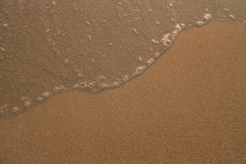 The texture of the sea beach sand with a soft lapping wave.