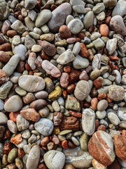 Pebbles on beach, as abstract background. Small colorful stones wallpaper. Sea stones with different sizes on the sea. Multicolored abstract nature pattern. Textured photography.