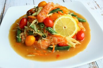 Spicy raw vegetables of papaya, carrot, green bean, cherry tomato with raw salmon on the plate photo