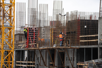 cranes and workers being poured concrete into foundation. Cement pouring into formwork of building at construction site. Tower cranes constructing a new residential build